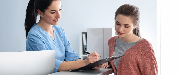 Dental-receptionist-looking-at-documents-with-patient